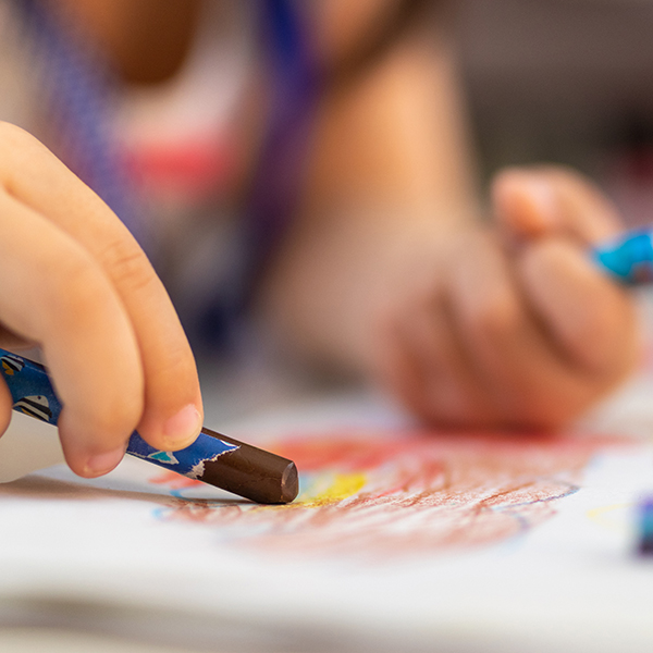 Close up of little hands coloring with Crayon