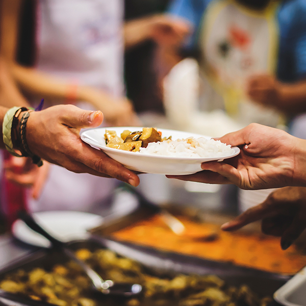 Homeless people receive delicious charity food from volunteers: concept of helping by donating food